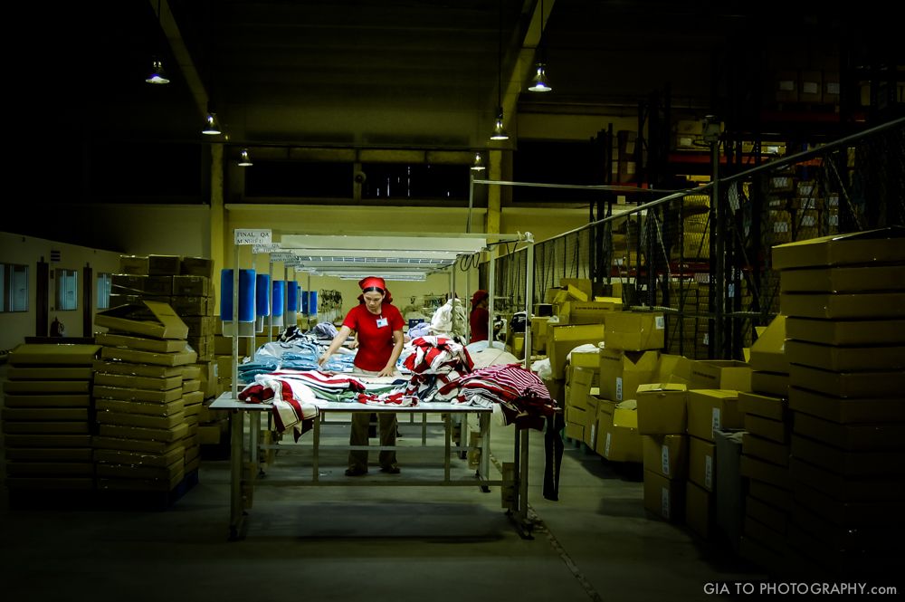 Woman at work in a garment factory in Viet-Nam. Her job is to make sure that these premium sport clothes ship to USA and Europe without defect. The special lighting of this scene reinforces her dedication. This woman is one of the reality of a developing country, not a cliche built for western eyes and expectations.